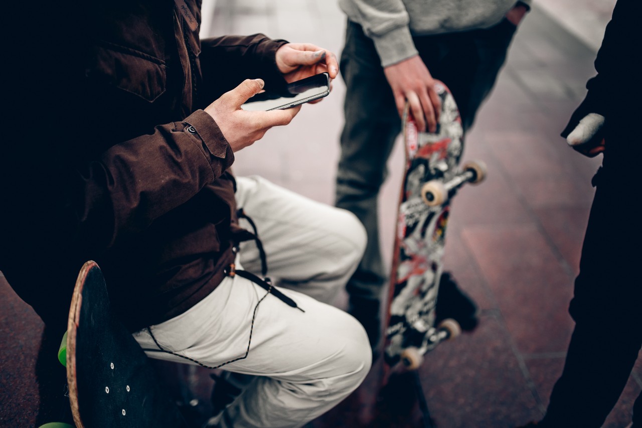 guy is holding the phone on the background Friends of the company of men holding their hands skateboards. Concept group of street athletes students social network