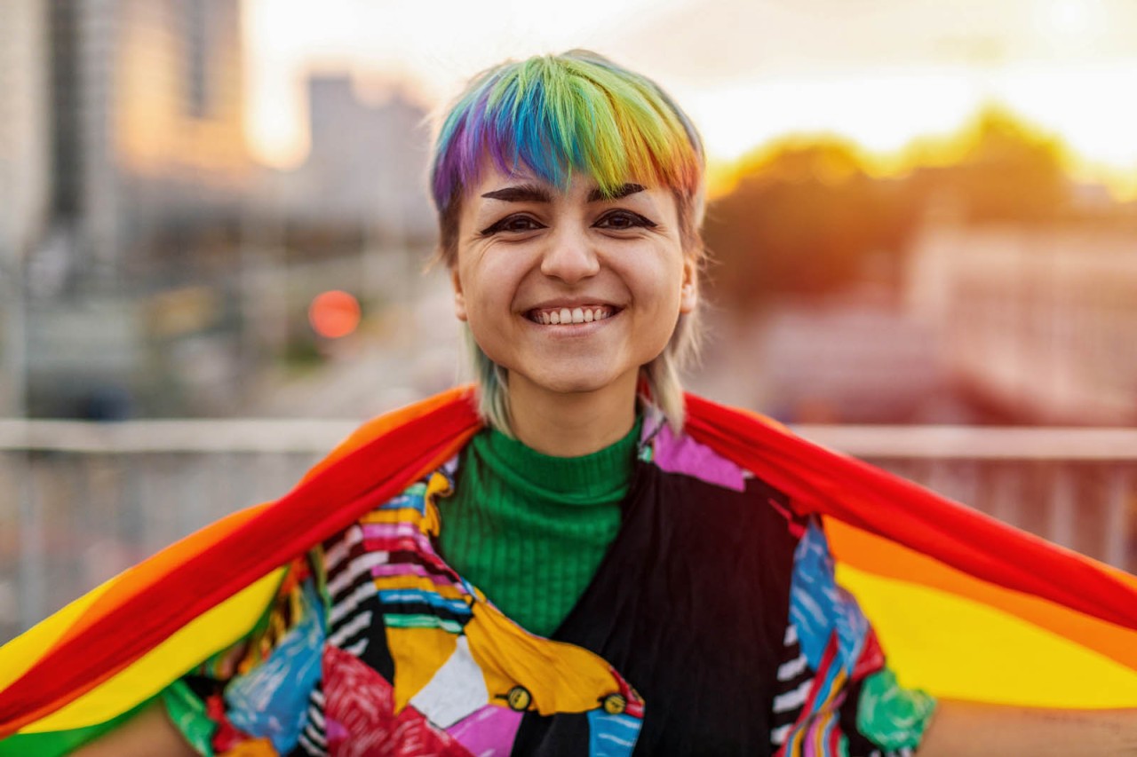 Portrait of a gender fluid person wearing rainbow flag